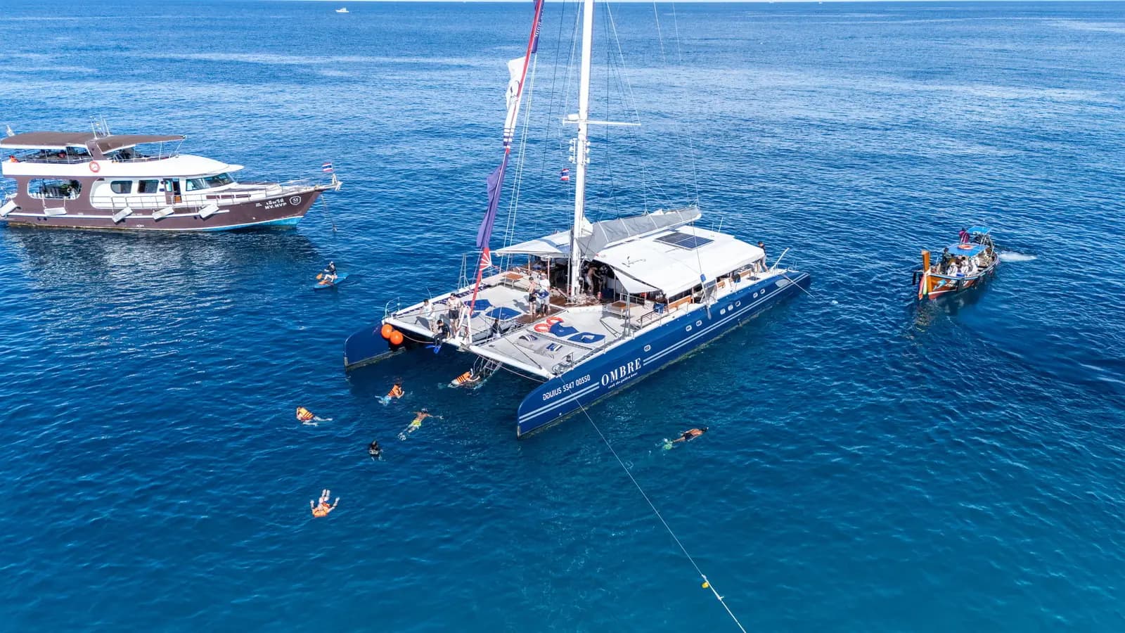 Aerial view of OMBRE anchored in deep blue sea with swimmers nearby
